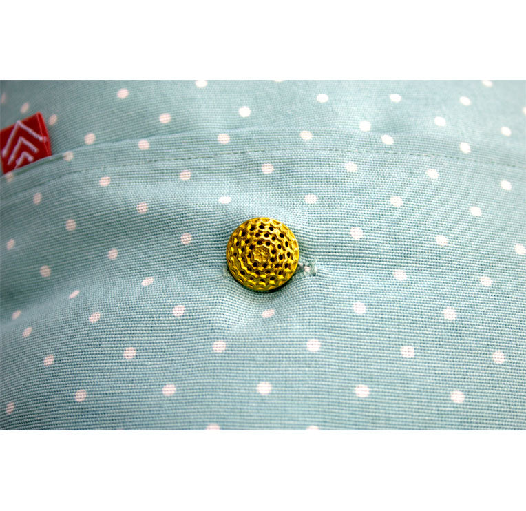 Detalle del botón dorado labrado del cojín con estampado de topitos. Ana de Valle. Remolona